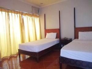 two beds in a room with two windows with curtains at DDD Habitat, Inc - Cagayan De Oro in Cagayan de Oro