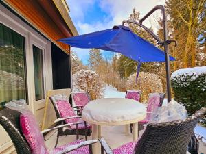 a table and chairs on a porch with an umbrella at Winterberg Appartement 6 Pers am Skilift größten Skigebiets, ruhige Garten im Wald, gemütlichen Après-Ski-Cafés Restaurants zu Fuß erreichbar, Parkplatz, Schwimmbad, Sauna, Relaxraum, Buchbaren Massages Wellness Der Brabander, Darts Tischtennis-Fußball in Winterberg
