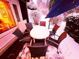 a table and chairs on a porch in the snow at Winterberg Appartement 6 Pers am Skilift größten Skigebiets, ruhige Garten im Wald, gemütlichen Après-Ski-Cafés Restaurants zu Fuß erreichbar, Parkplatz, Schwimmbad, Sauna, Relaxraum, Buchbaren Massages Wellness Der Brabander, Darts Tischtennis-Fußball in Winterberg