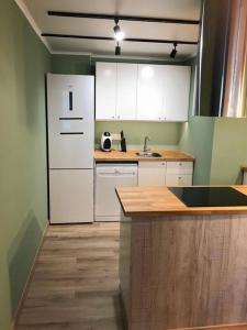 Una cocina con gabinetes blancos y un refrigerador blanco. en Beach apartment 2 terraces with parking, en Castelldefels