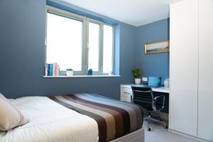 a bedroom with blue walls and a bed and a desk at London Bridge Escape - 2 Bed 2 Bath near landmarks in London