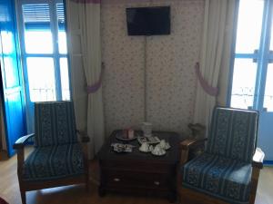 Pokój z dwoma krzesłami, stołem i telewizorem w obiekcie Balneario La Encarnacion w mieście Los Alcázares