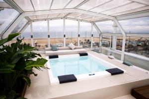 a swimming pool in the middle of a building with a glass ceiling at Hotel De Londres in Rimini