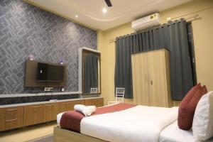 古瓦哈提Hotel Pohor Regency Near Kamakhya Gate Foot Bridge的一间带床和平板电视的卧室