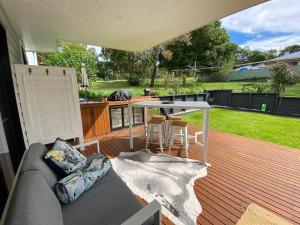 a patio with a couch and a table on a deck at Golf Course & Beach Stay Self-Contained Guest House in Nelson Bay