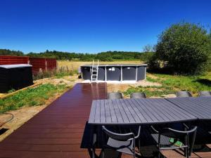 eine Holzterrasse mit Tisch und Stühlen und einem Gebäude in der Unterkunft Aux portes de Chambord in Dhuizon