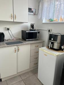 uma cozinha com armários brancos e um micro-ondas em 50 on Cap em Bloemfontein mais 11 fotografias