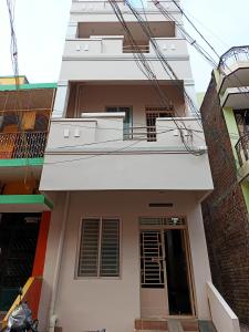 a white building with a balcony and a door at Aalaya Darshan Homestay in Tiruvannāmalai