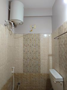 a bathroom with a toilet and a light on the wall at Aalaya Darshan Homestay in Tiruvannāmalai +36 photos
