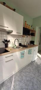 a kitchen with white cabinets and a sink at Igali Varázs Apartman 2 perc a fürdőtől in Igal