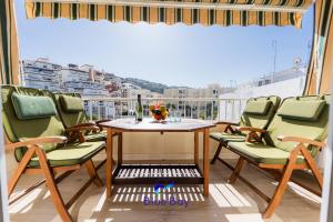 Un balcón con una mesa y sillas y una ventana. en White Bay Beach Apartment, en La Herradura
