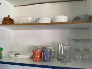 a shelf with cups and other glass items on it at casa Marcela papudo in Papudo +10 photos