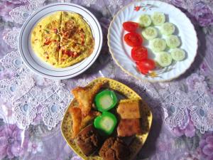 a table with two plates of food and a pizza at Kurnia Homestay in Ternate