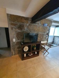 un soggiorno con una tv e un muro di pietra di Casa do Tinte - Gouveia-Folgosinho a Vila Cortês da Serra