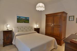 Un dormitorio con una cama blanca y un armario de madera. en Villa Torre Bianca - Luxury Home, en Manduria