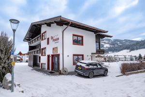 a car parked in front of a building in the snow at Au Pension in Söll