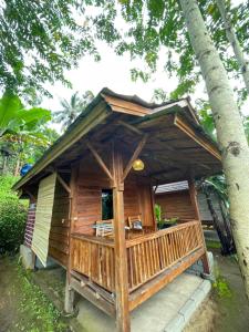 特特巴图Serenity Lodge Tetebatu Lombok的小木屋设有门廊和一棵树