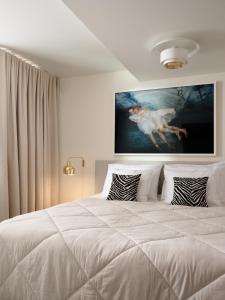 a bedroom with a white bed with a painting on the wall at Finlandia Homes in Helsinki