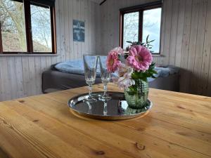 a table with two glasses and a vase with flowers at Hyggelig hytte - perfekt til par in Hundested