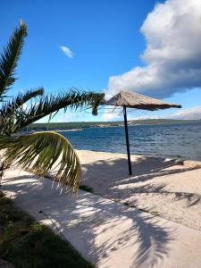 una playa con sombrilla de paja y agua en Jimis Apartmani, en Dubraja