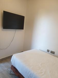 Un dormitorio con una cama y un televisor de pantalla plana en la pared. en Starlight tiny home, en Lotus Island
