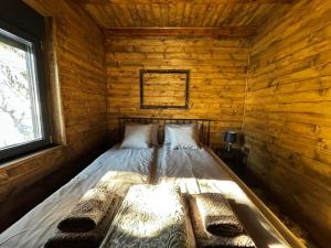 a bed in a log cabin with a window at Cabins Dolce Vita in Konjska Reka
