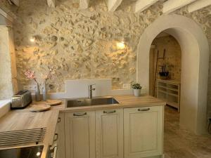 a kitchen with a sink and a stone wall at Le Cottage Lascaux in Bourrou