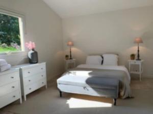 a white bedroom with two beds and a window at Le Cottage Lascaux in Bourrou