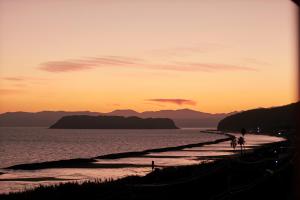 a group of people walking along a beach at sunset at Koran no Yu Kinkouro in Ibusuki