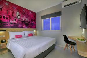 a bedroom with a large bed with a red painting on the wall at favehotel Ahmad Yani Banjarmasin in Banjarmasin