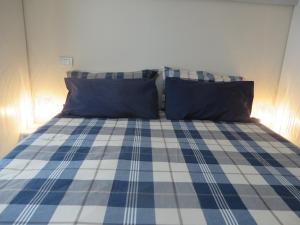 un letto con lenzuola e cuscini blu e bianchi a quadri di Alloggio turistico Maison S Anselme VDA Aosta CIR 0015 ad Aosta