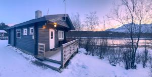 a small cabin in the snow with a fence at Strandbu Camping in Skibotn