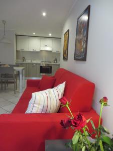 un divano rosso in un soggiorno con cucina di Alloggio turistico Maison S Anselme VDA Aosta CIR 0015 ad Aosta