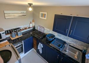 a kitchen with blue cabinets and a sink at Willow Cottage in Horning +1 photo