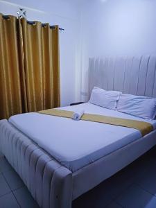 a large bed in a room with curtains and a bedskirtspectspects at Cozy 2 bedroom Apartment at Mombasa Island in Mombasa