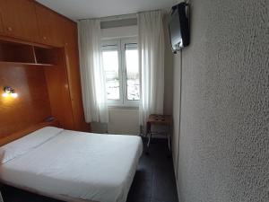 a small bedroom with a bed and a television at Puente Azud in Avilés