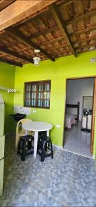 a table and chairs in a room with a green wall at RECANTO MARTIM de SÁ in Caraguatatuba