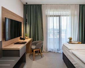 a hotel room with a bed and a desk with a television at Hotel Sevtopolis Medical & SPA in Pavel Banya +50 photos