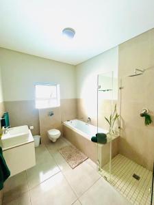 een badkamer met een bad, een toilet en een wastafel bij Sakkie se Dakkie in Agulhas +11 foto's