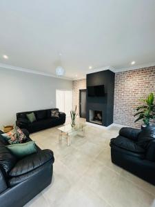 a living room with black leather couches and a fireplace at Sakkie se Dakkie in Agulhas