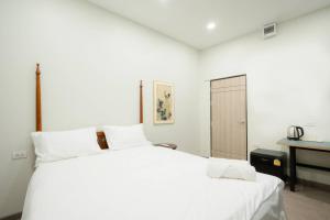 a white bedroom with a large bed and a desk at CASA Yaowarat Road ถนนเยาวราช in Samphanthawong