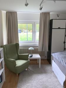 a bedroom with a green chair and a bed at Apartment Isenbügel / Essen-Kettwig in Heiligenhaus