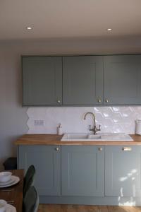 a kitchen with blue cabinets and a sink at Southview Barkisland in Halifax +56 photos