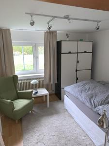 a bedroom with a bed and a chair and window at Apartment Isenbügel / Essen-Kettwig in Heiligenhaus