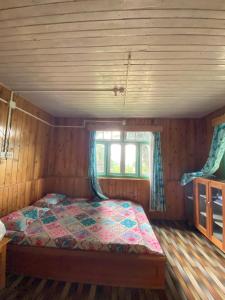 a bedroom with a bed in a room with a window at Shangdhan Pine Homestay in Sāmthar
