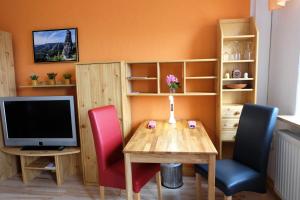 a dining room with a table and chairs and a television at Panoramablick in Sebnitz +6 photos