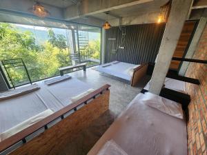 a room with two beds and a large window at The Wildwood Retreat KKB in Kuala Kubu Baharu
