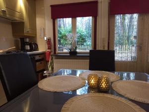 een keuken met een glazen tafel met twee kaarsen erop bij Chalet Bosrust in Lanaken +2 foto's