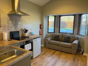 a living room with a couch and a kitchen at Rowandell Highland Studio in Fort William