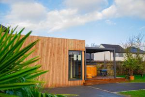 a small house with a wooden wall and a patio at studio Avec piscine et Spa Privatif Extérieur 4 personnes in Lestrem